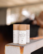 Three tubes of Bareback Botanical's 'Braid Beehave' on a metal surface with a blurred background.
