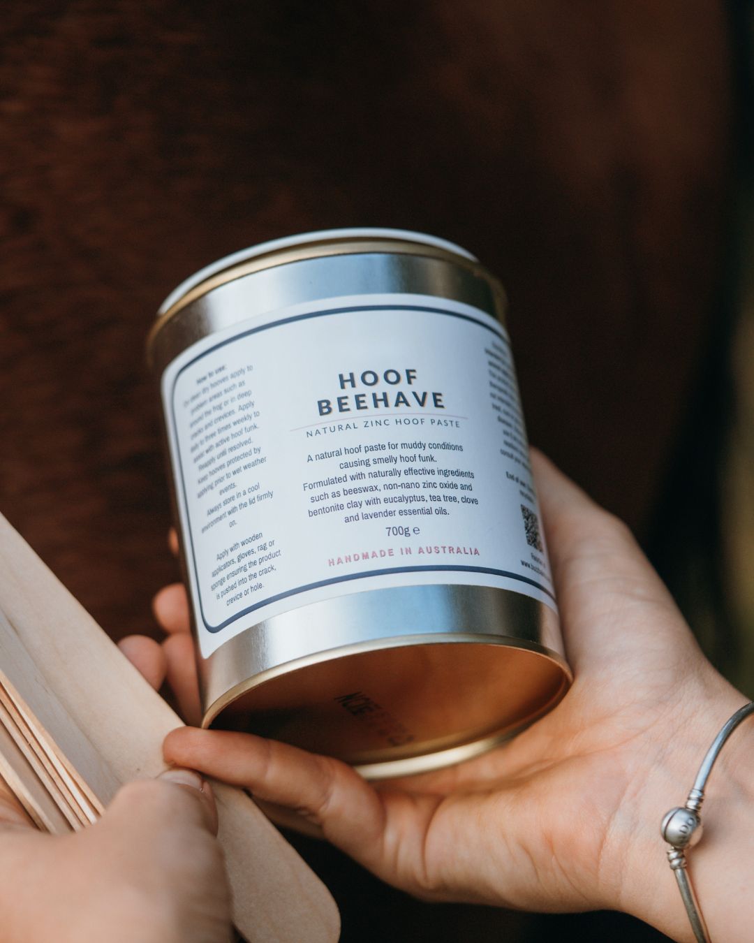 Can of 'Hoof Beehave' product held by a person with a blurred background