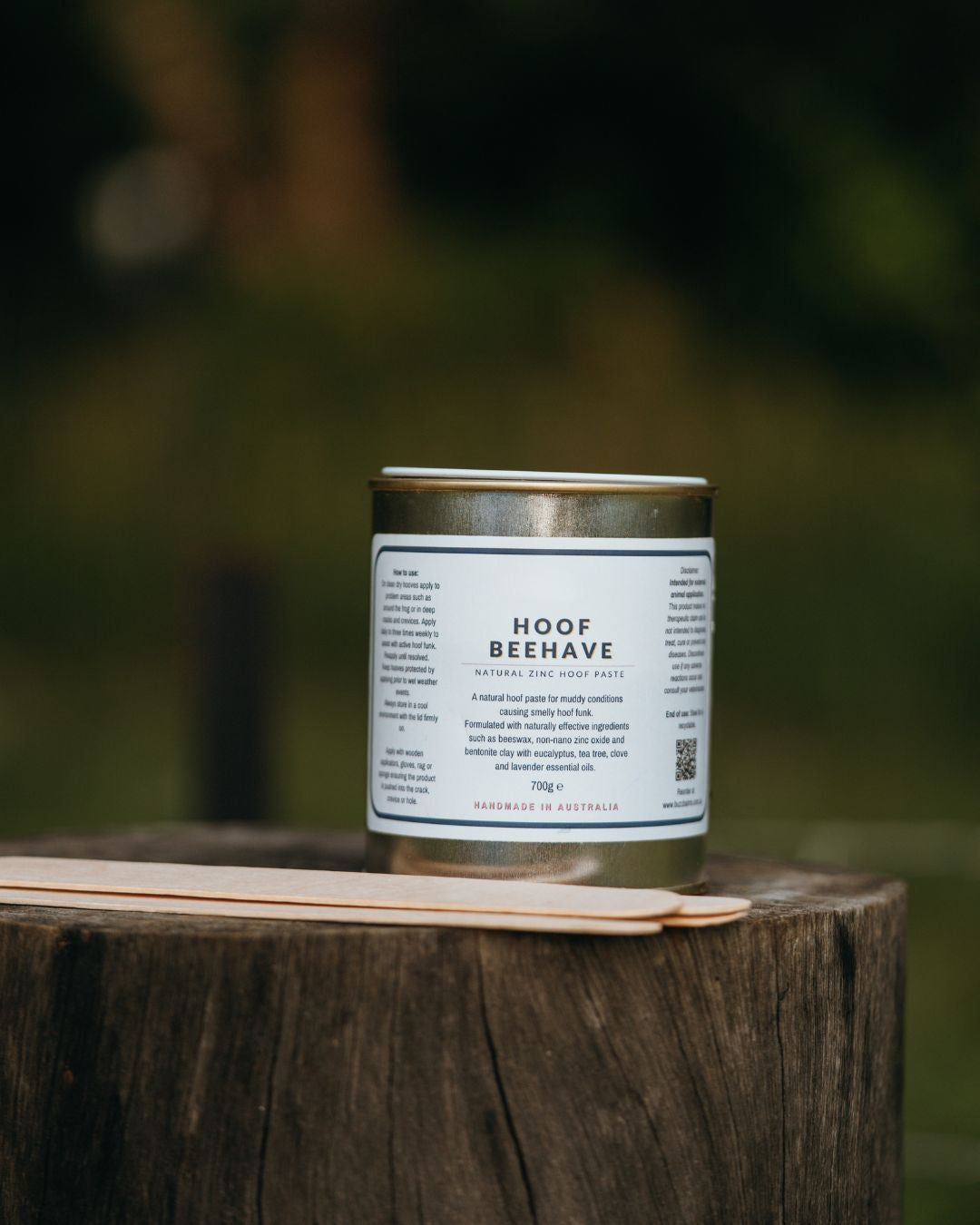 Canister labeled 'Hoof Beehave' on a wooden surface with a blurred natural background